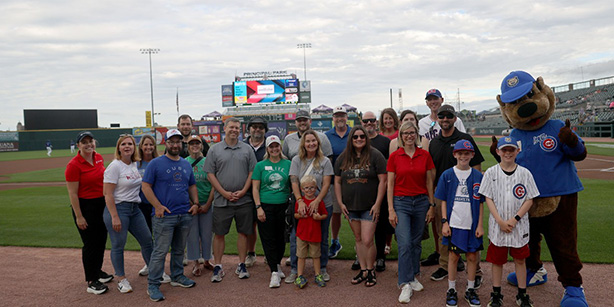 A group of people smiling on a baseball field.